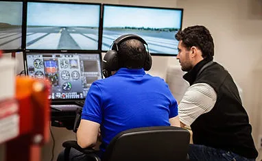 Student and CFI sit down in front of a Redbird flight simulator